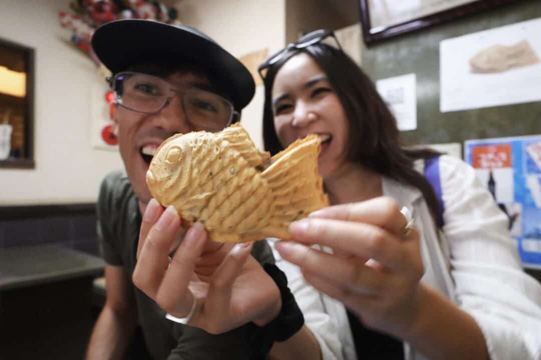 Happy couple eating Taiyaki Wakaba on a Tokyo bicycle food tour