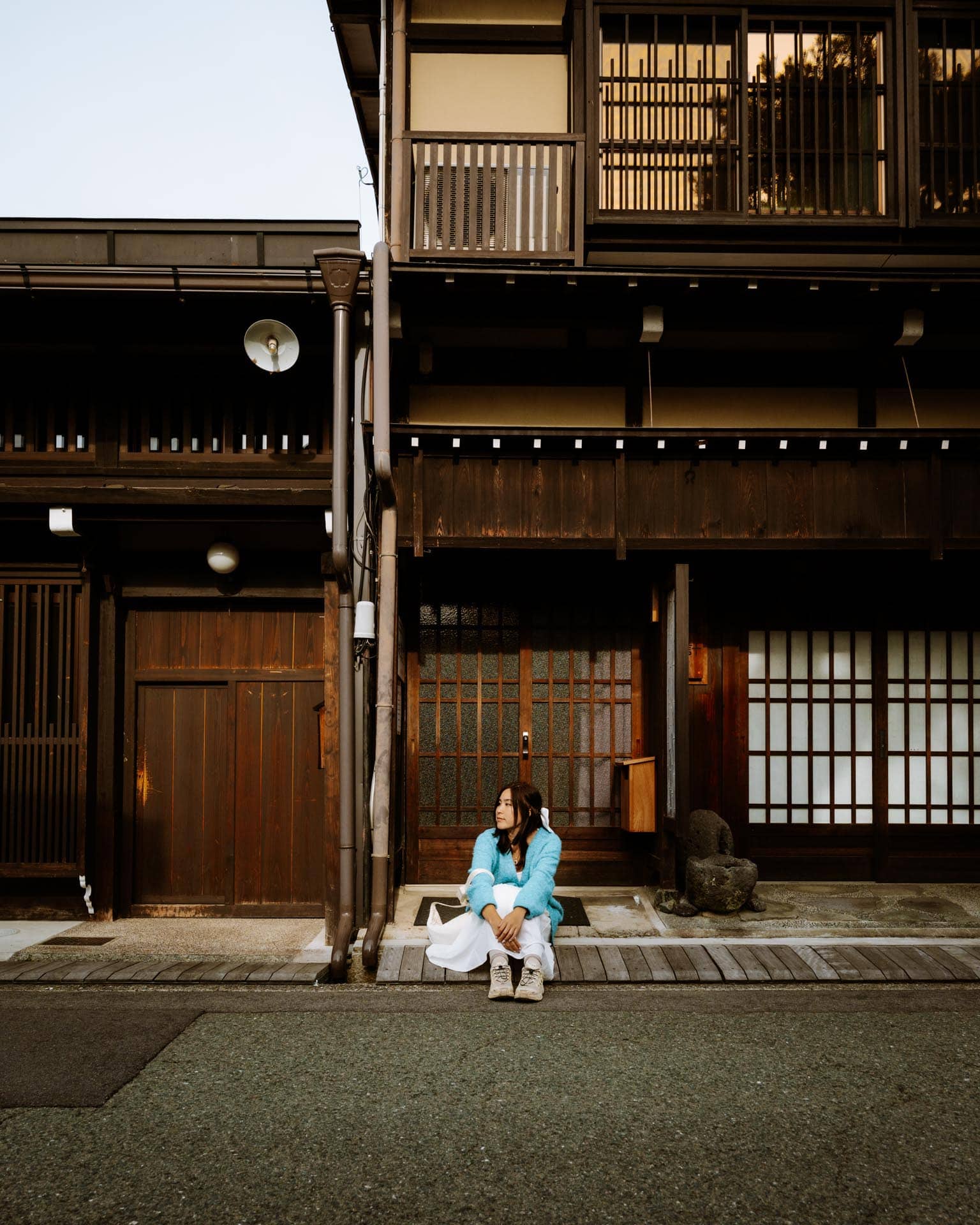 Woman sits on street at Homeitaigumi Preservation Area in Takayama, Japan