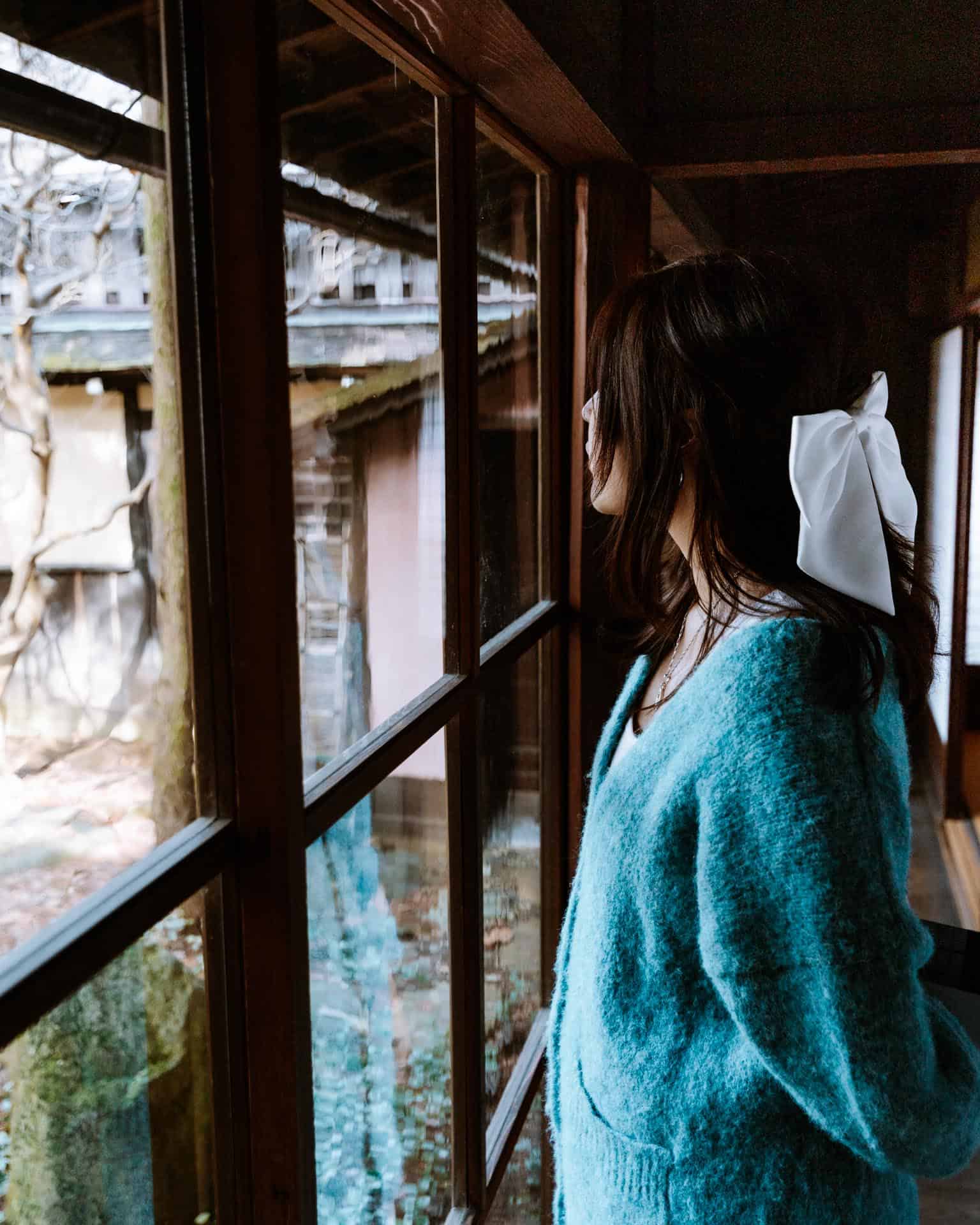 Woman looks out window to Japanese Garden at Kusakabe Traditional House in Takayama, Japan