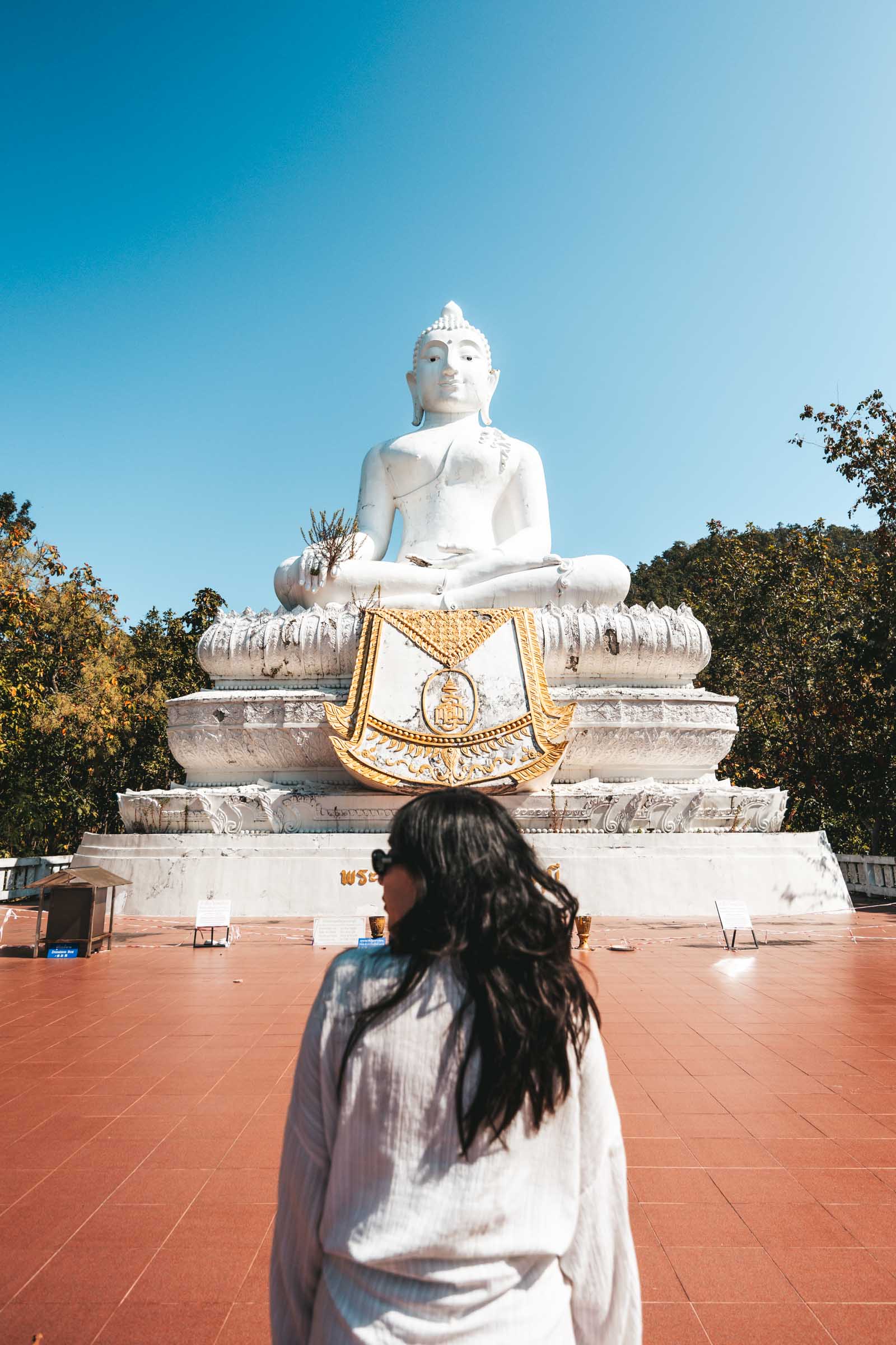 Chloe standing at Big Buddha in Pai